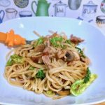 Child's portion of pulled pork noodles with savoy cabbage in a white bowl with plastic orange fork.