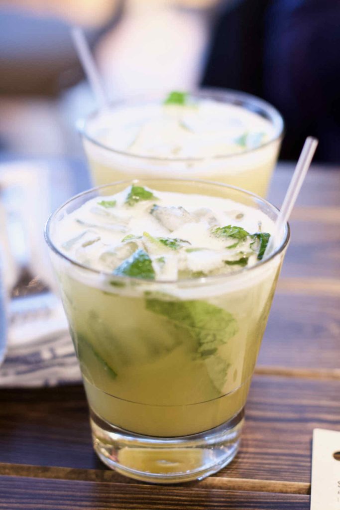 A pair of pale green Mai Tai cocktails in short glass tumblers with ice cubes, mint and clear plastic straws as served by Turtle Bay Caribbean style restaurant, Walthamstow branch East London.