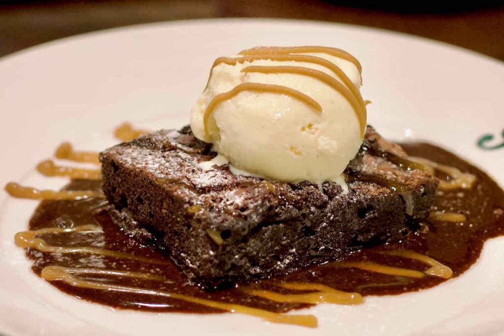 Brownie dessert in chocolate sauce adorned with scoop of vanilla ice cream and zig zag of caramel, as served at All Star Lanes bowling alley, Westfield Stratford, East London.