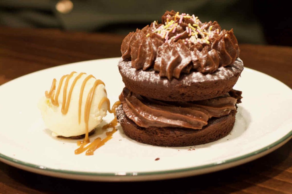 Chocolate whoopie pie dessert with piped icing, sprinkles and a scoop of vanilla ice-cream zig zagged with caramel sauce; as served at All Star Lanes bowling alley, Westfield Stratford, East London.