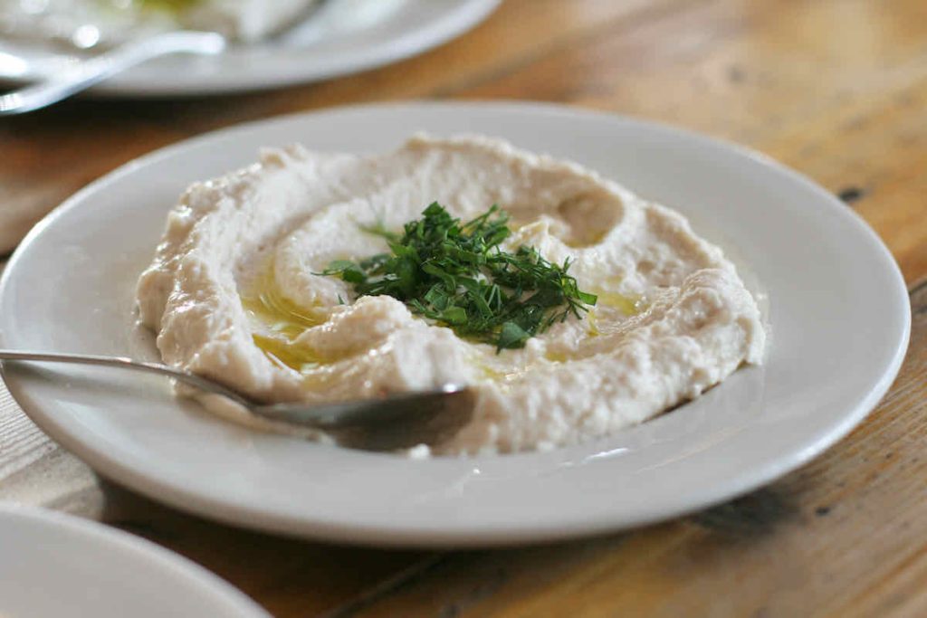 A white plate of white taramasalata cod roe dip garnished with dill, as served at The Real Greek restaurant at Westfield Stratford, East London.